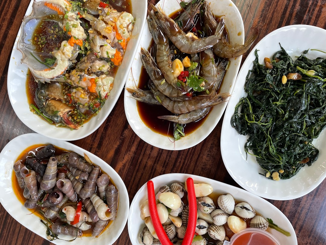 Five plates of seafood and vegetables on table