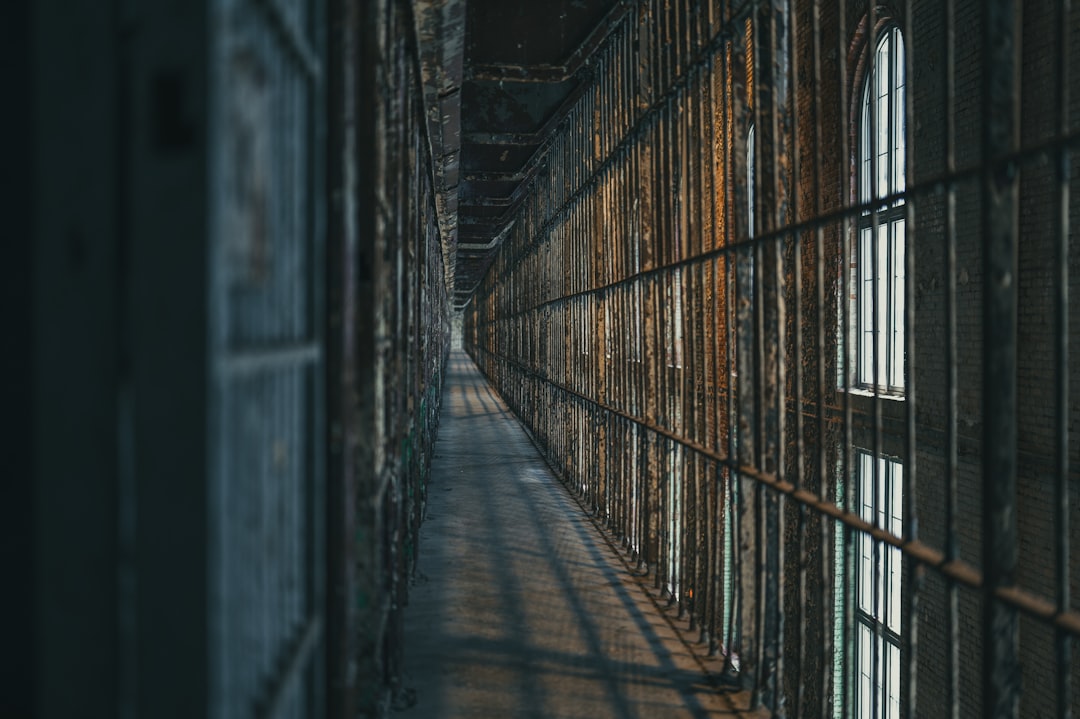 Dimly lit prison corridor with barred cells.